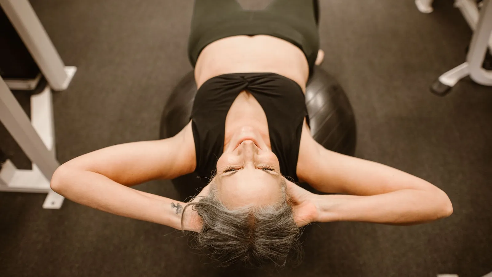 A woman lying on her back on an exercise mat, seen from above