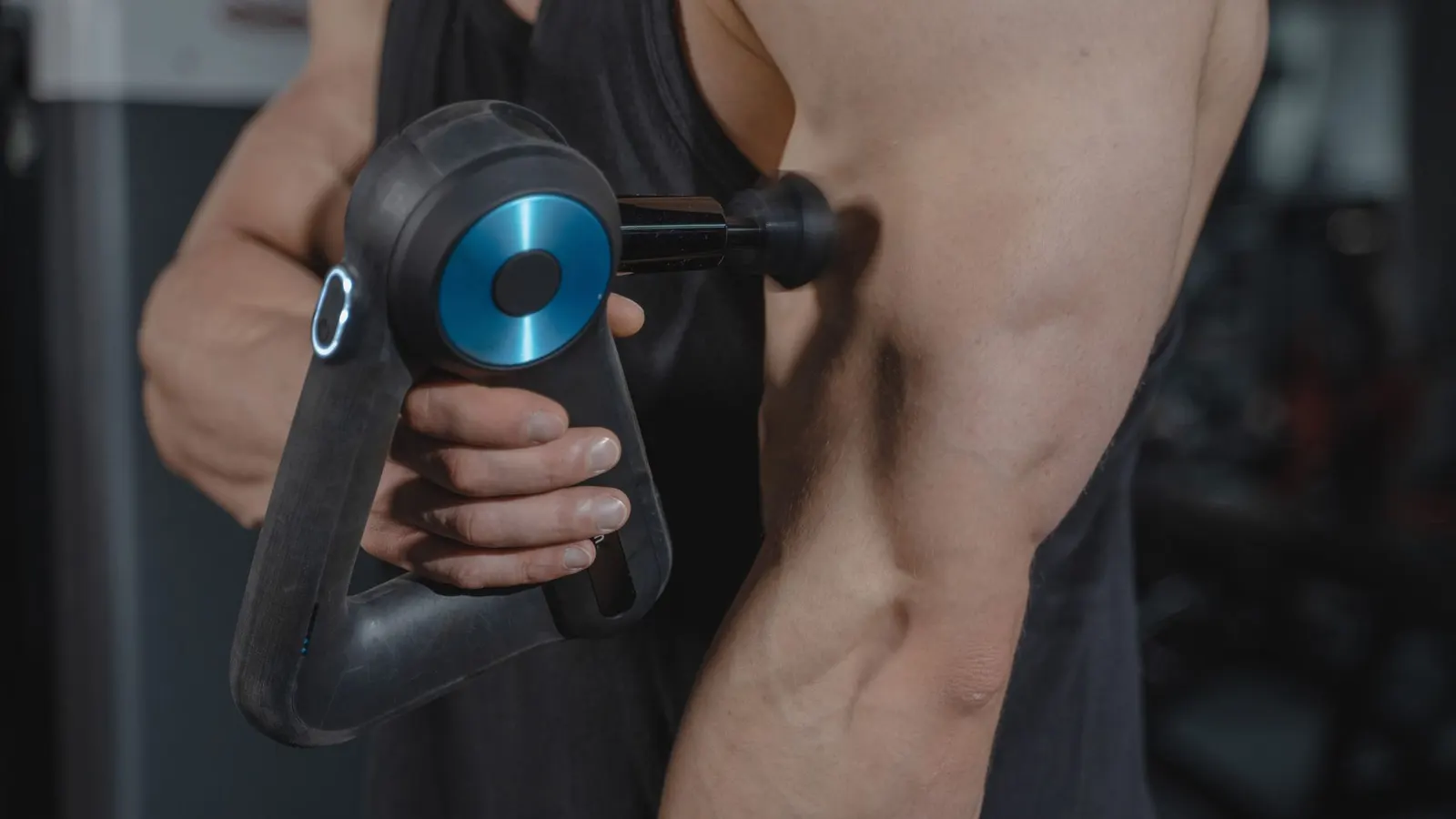 A massage gun pressed against the back of an arm