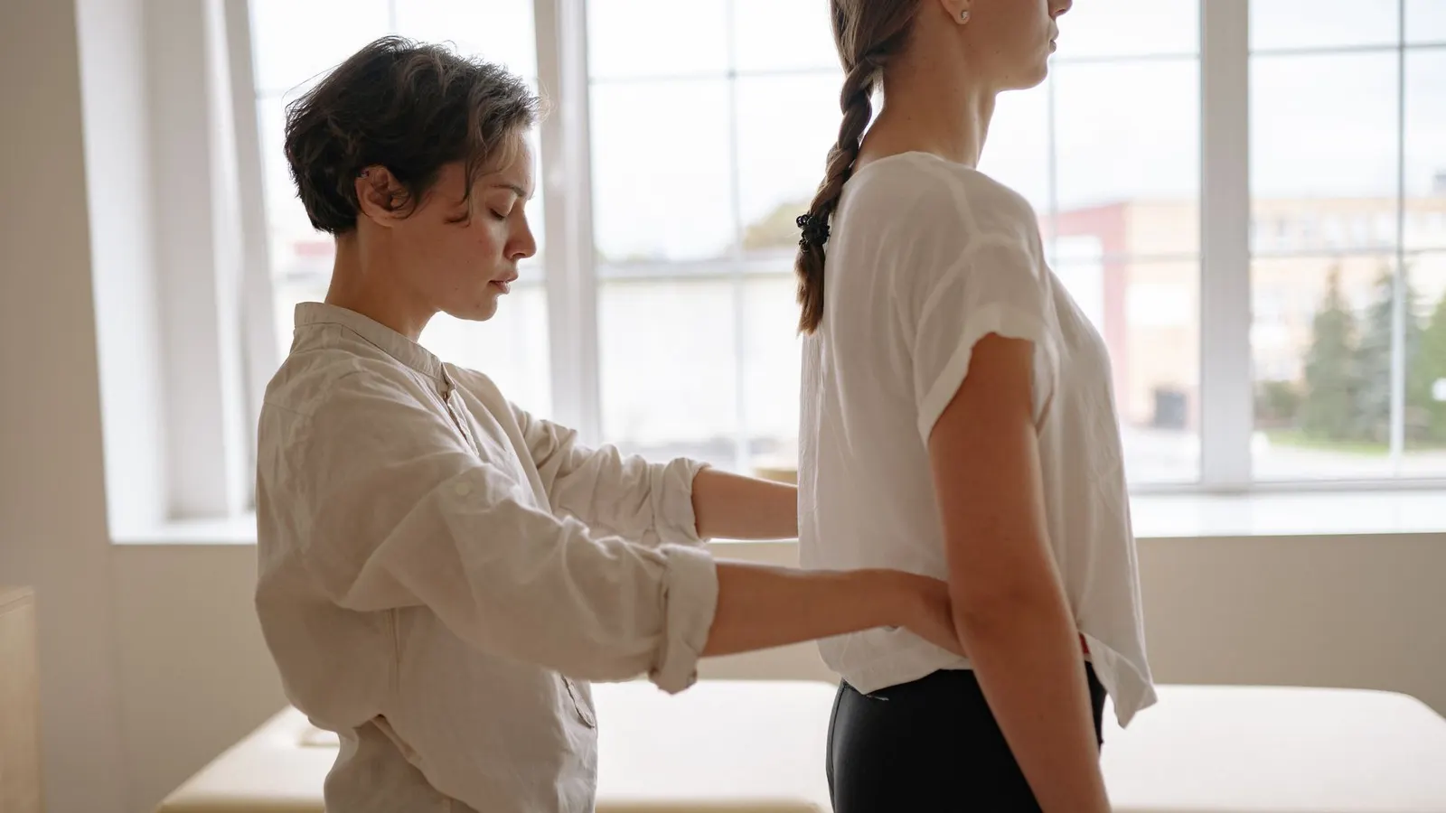 A physiotherapist assessing a patient's standing posture from the side