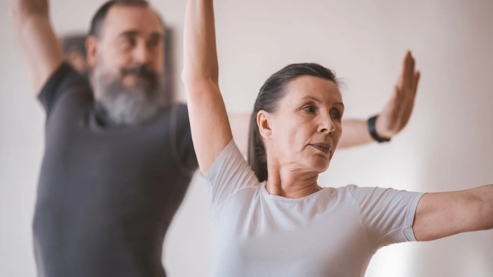 Two older adults practising a balance exercise with arms raised