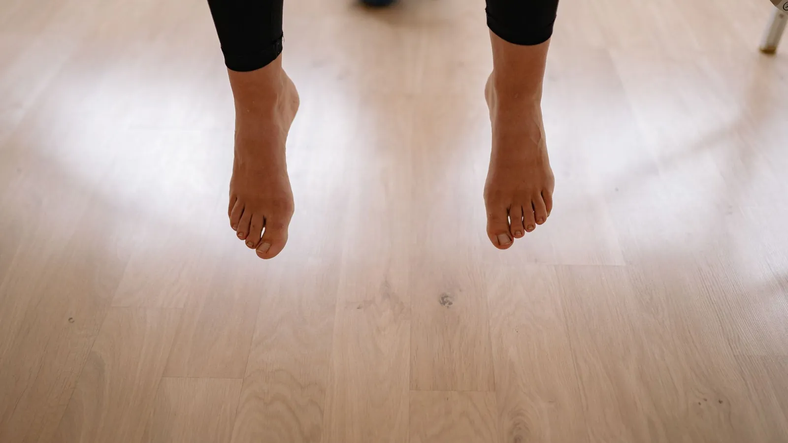 Bare feet standing on a wooden floor