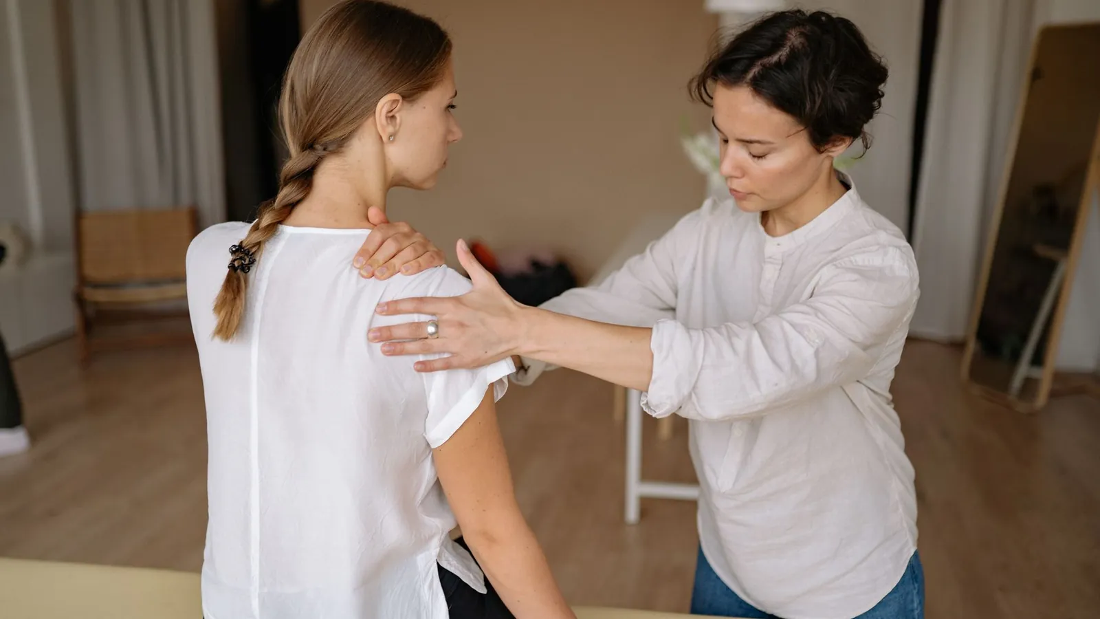 A physiotherapist assessing a patient's shoulder from behind