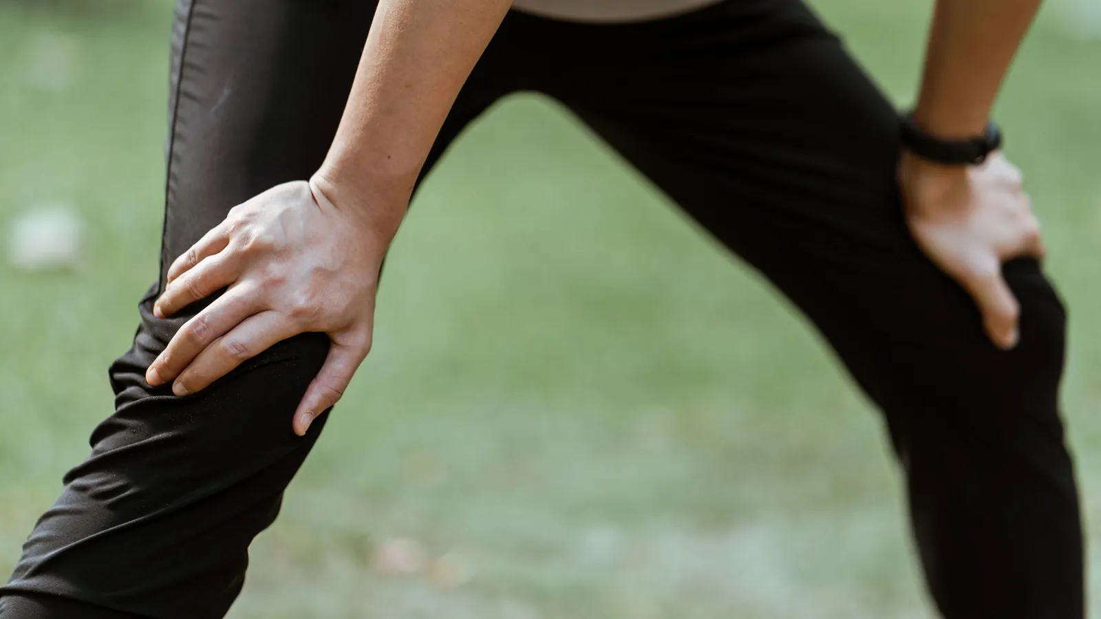 A person pausing on stairs holding their knee