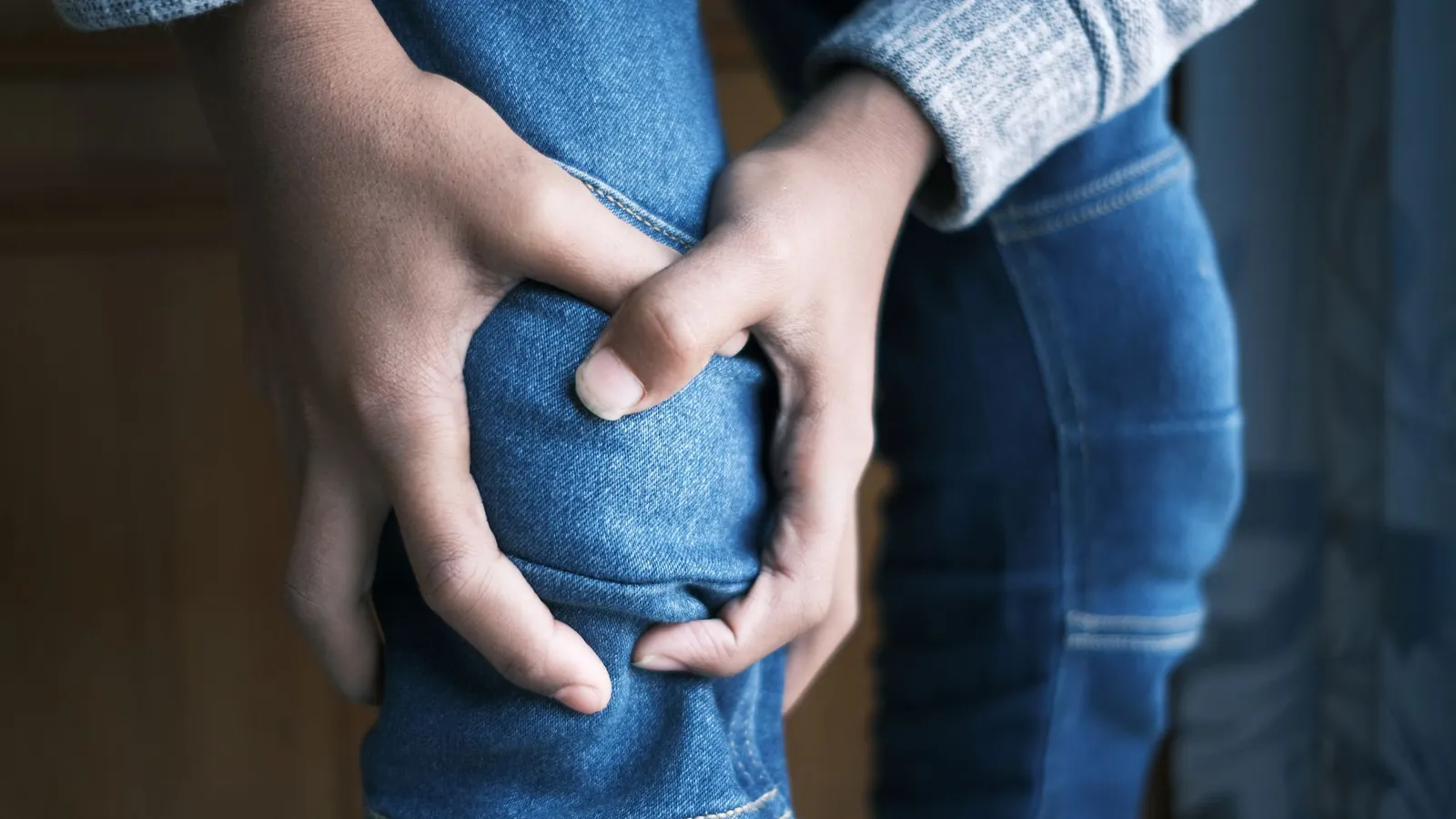 A person gripping their calf with both hands
