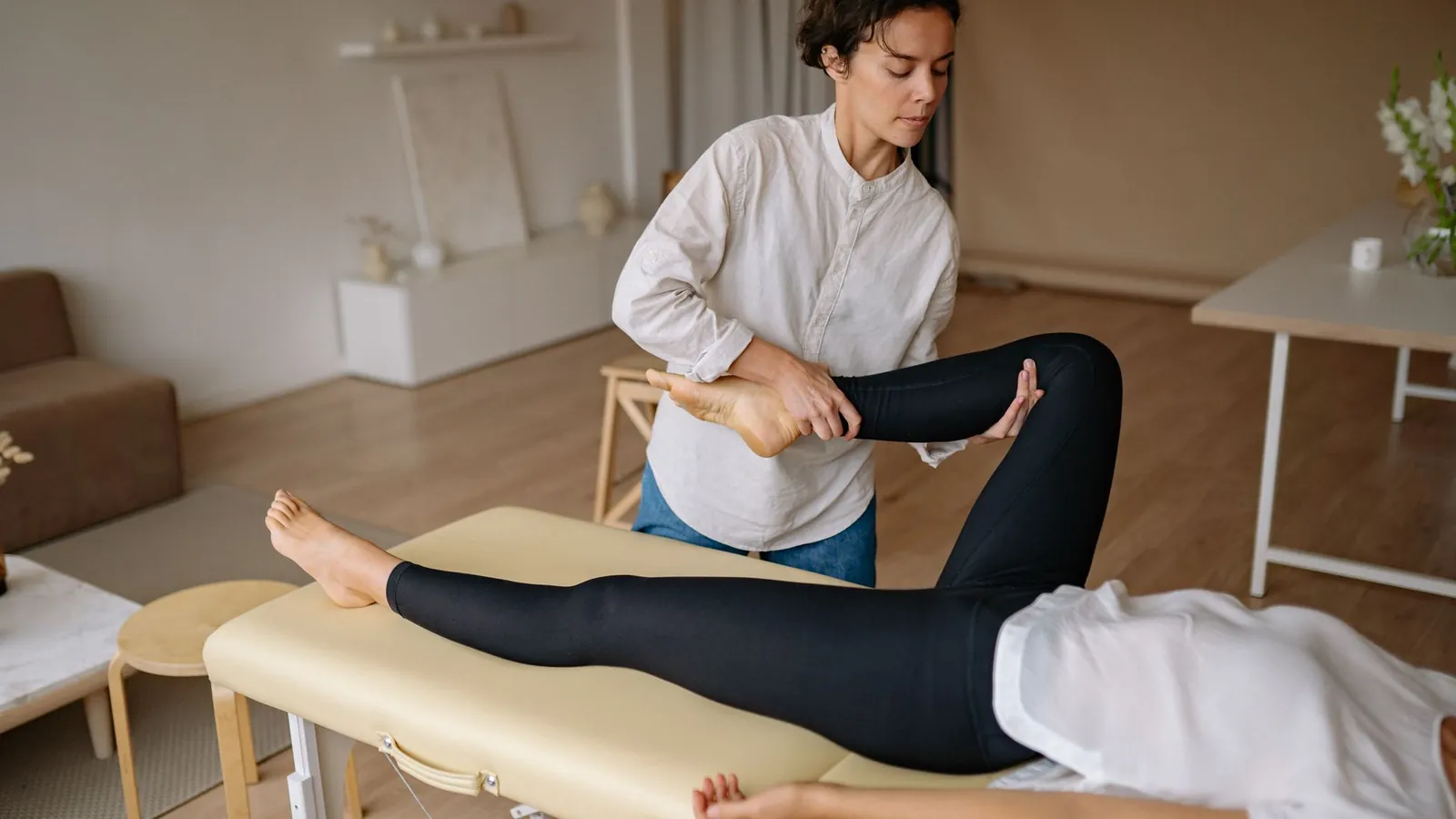 A physiotherapist raising a patient's straight leg during an assessment