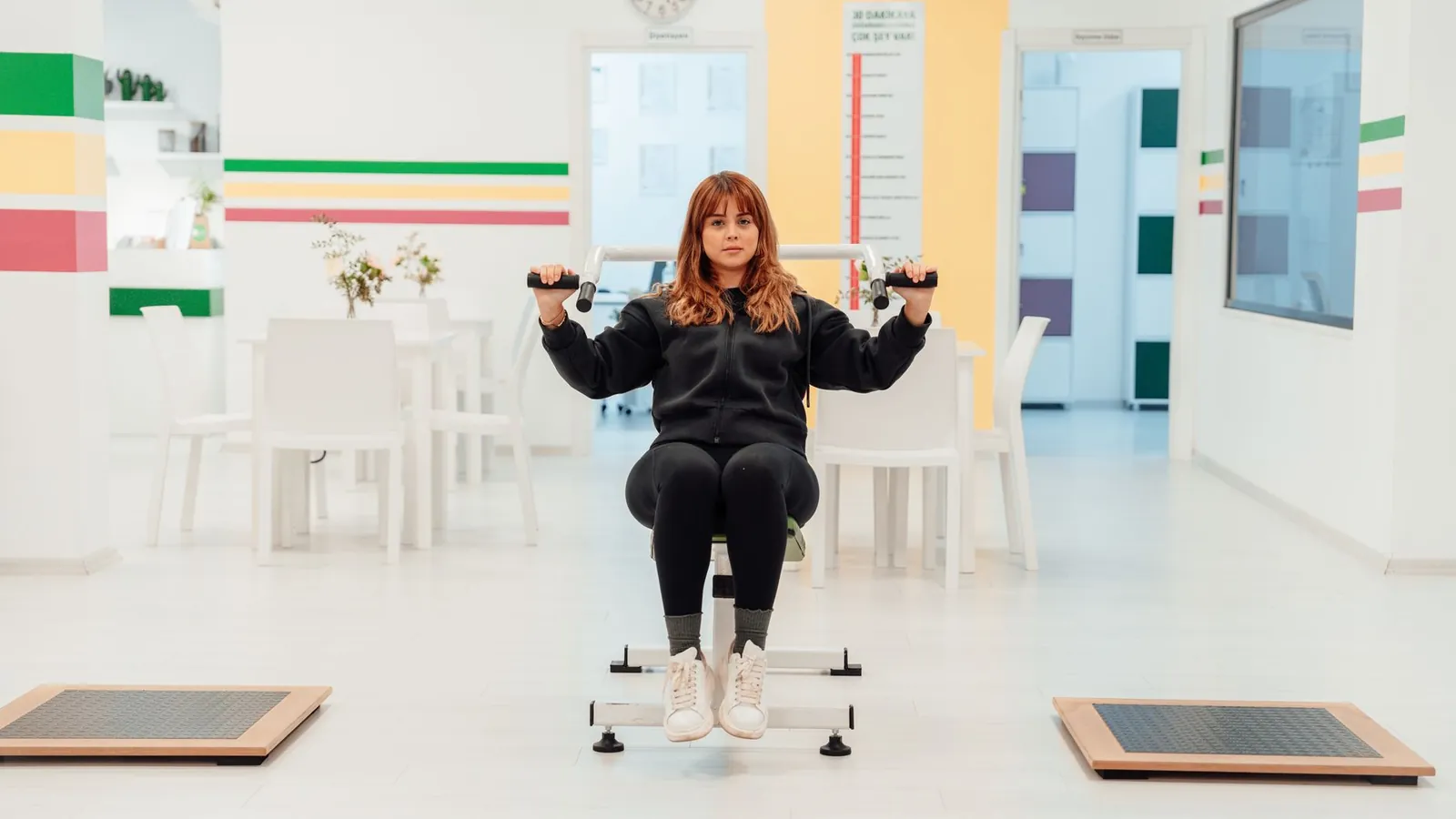 A woman doing seated dumbbell exercises in a rehabilitation gym
