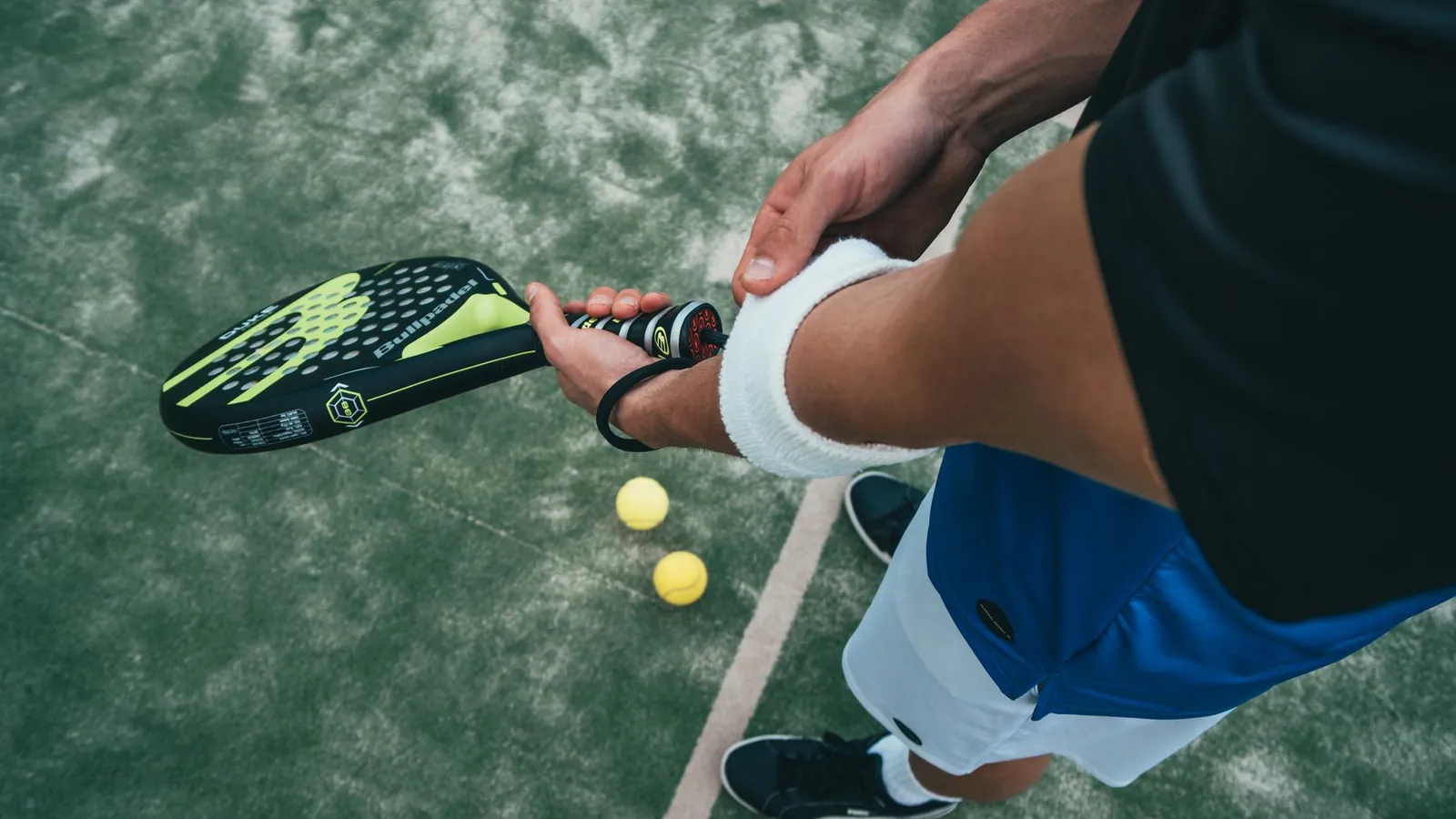 A tennis player with a support strap on the elbow holding a racquet