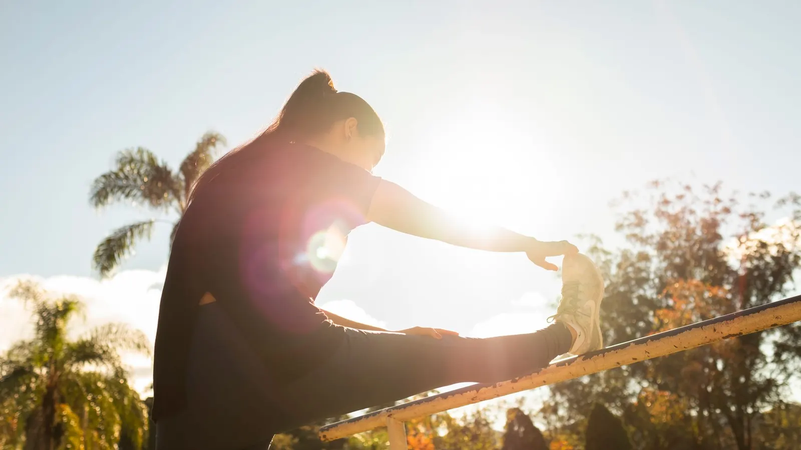 A woman stretching outdoors in early morning sunlight