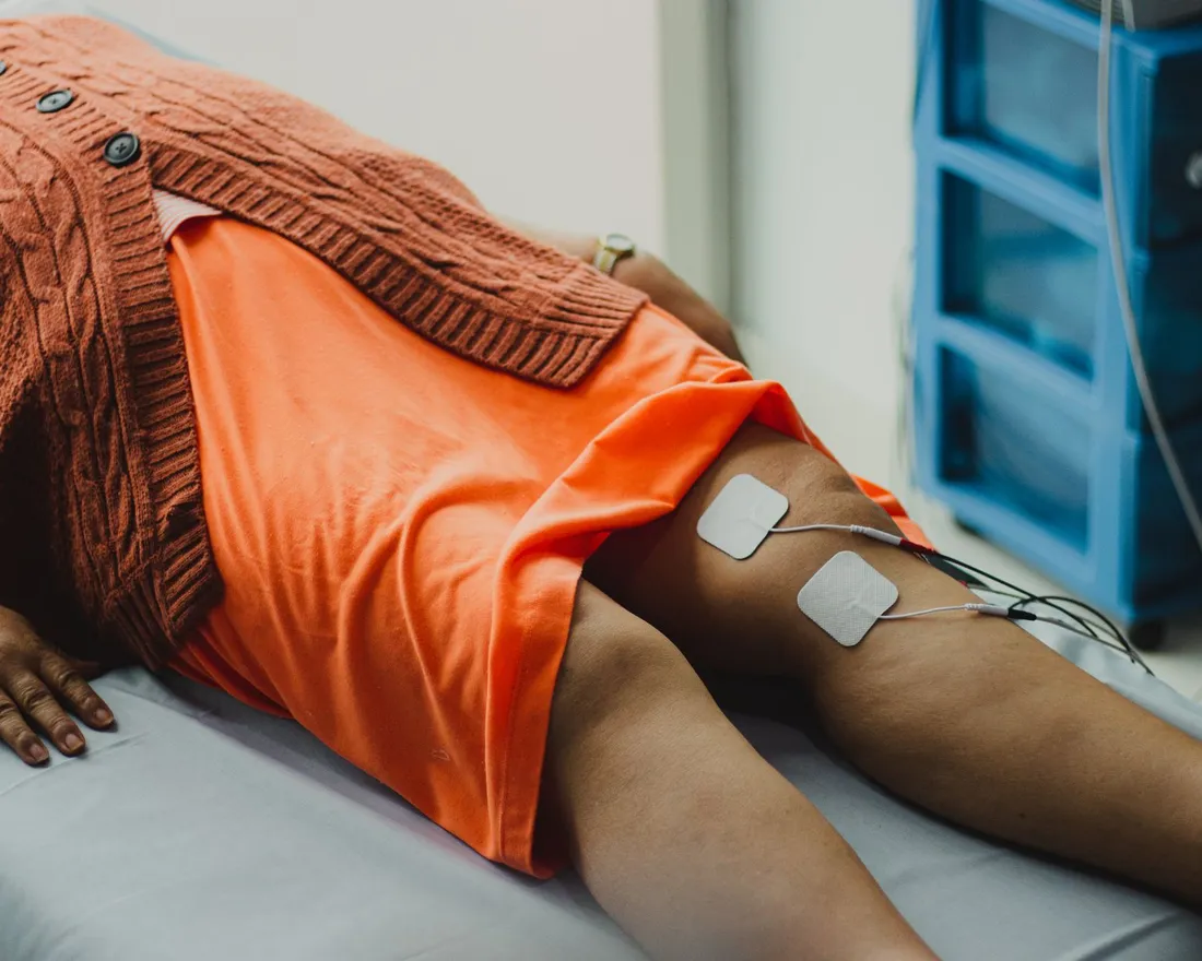 Electrotherapy pads placed around a patient's knee during a rehabilitation session